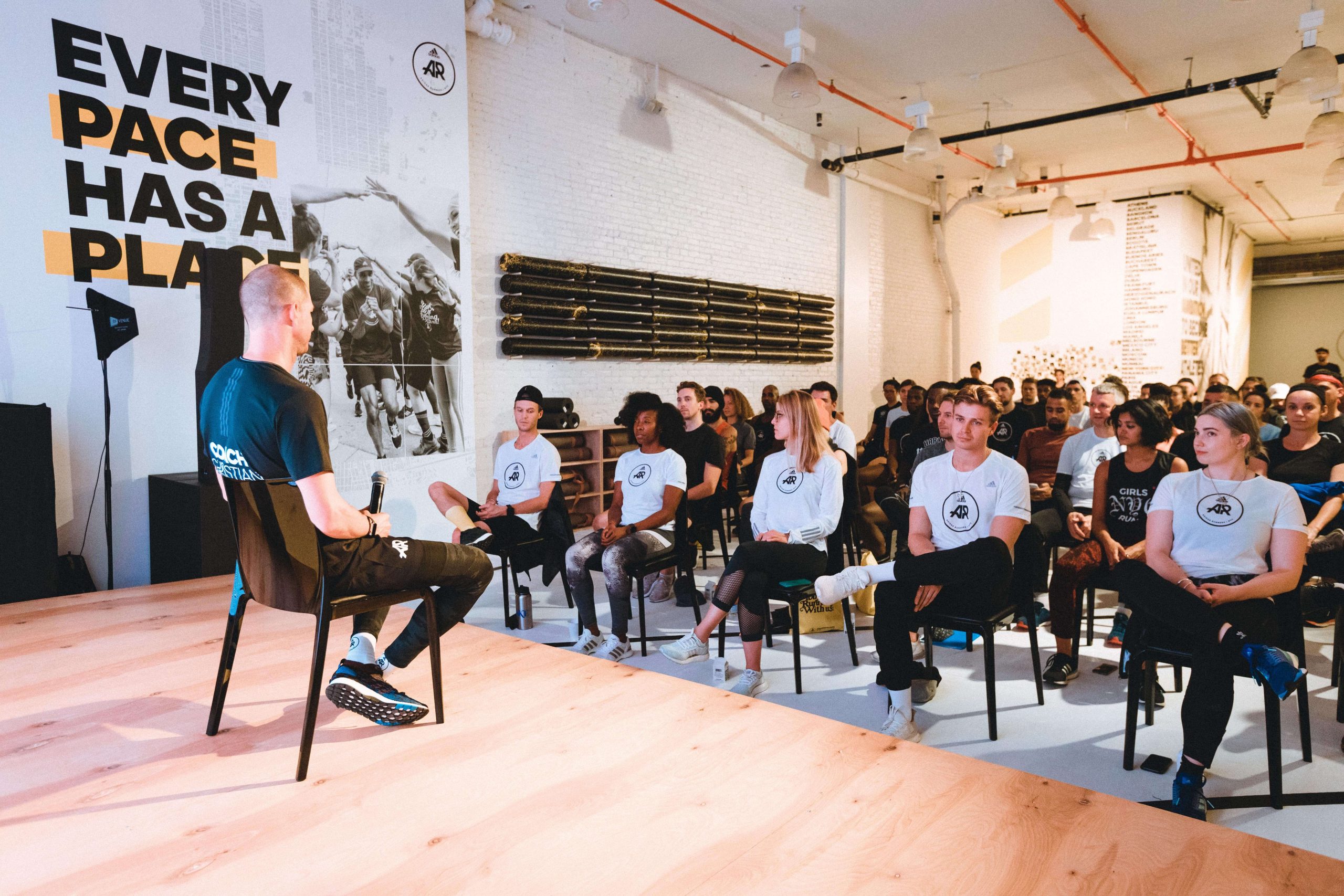 Christian Straka speaking at an adidas Runners event, full room of athletes